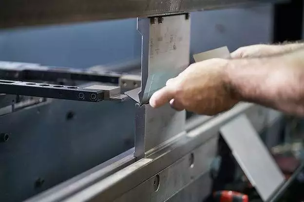 A man performing custom metal fabrication on a machine.